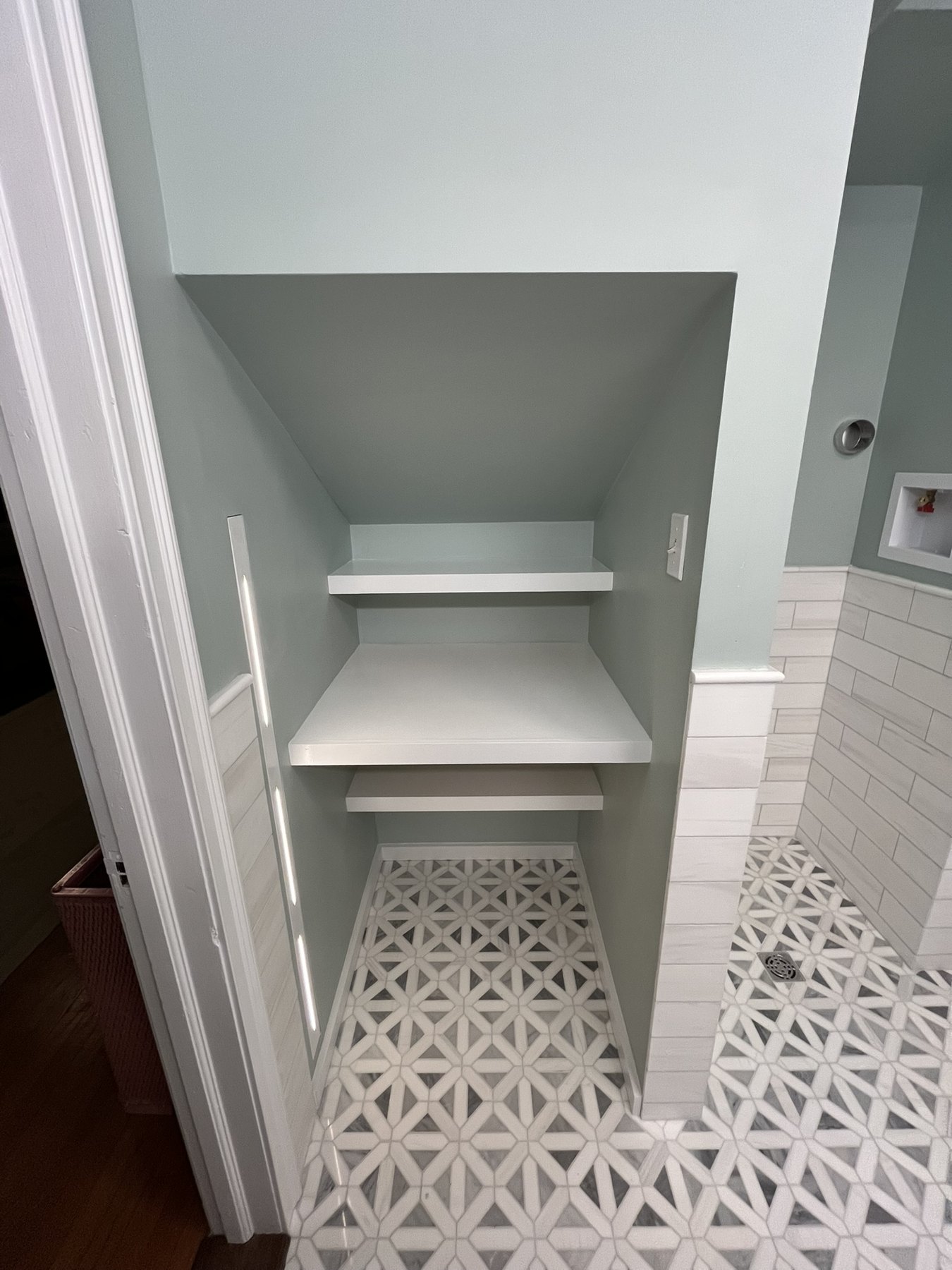 Fitted shelves beneath a sloping ceiling beside the bathroom